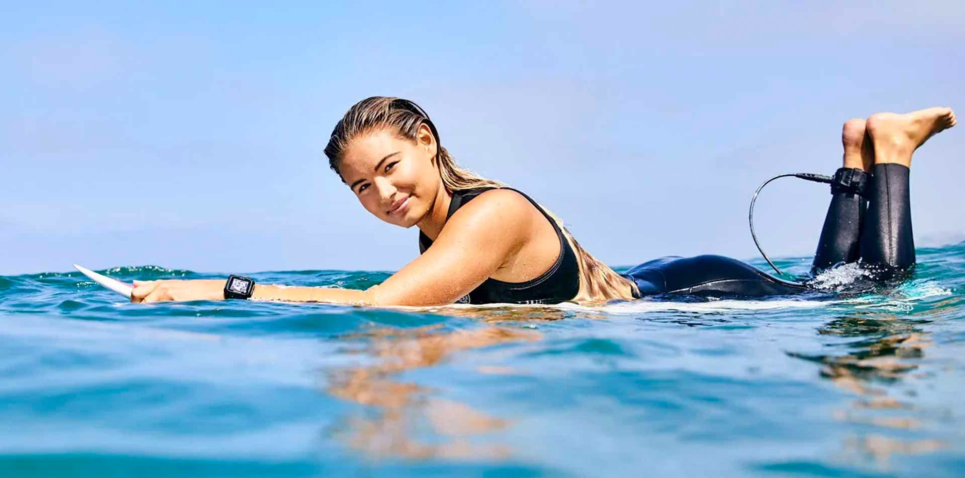 Leah Thompson laying on her surfboard in the ocean.