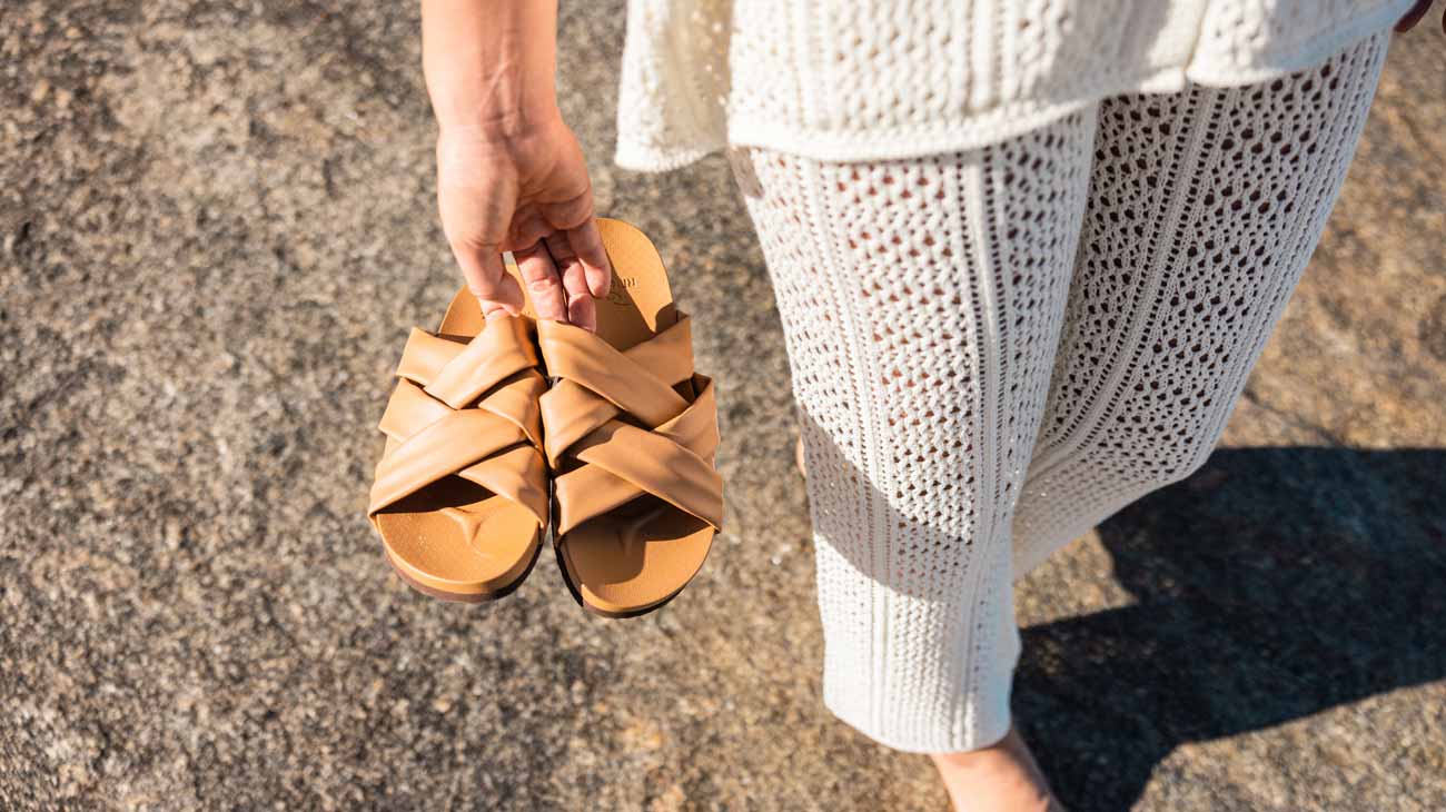 Model holding a pair of brown Rip Curl sandals