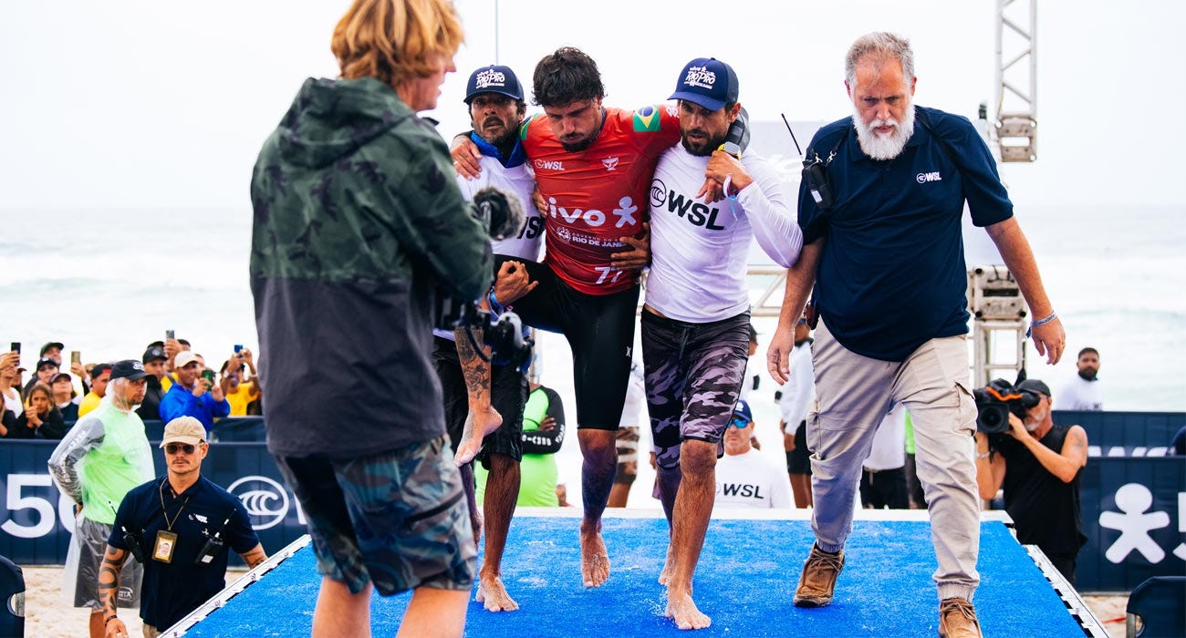 Filipe Toledo being carried back up the beach after suffering a potential knee injury. 