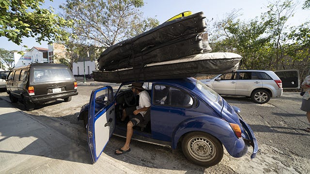 Board bags stacked up on top of a VW Bug