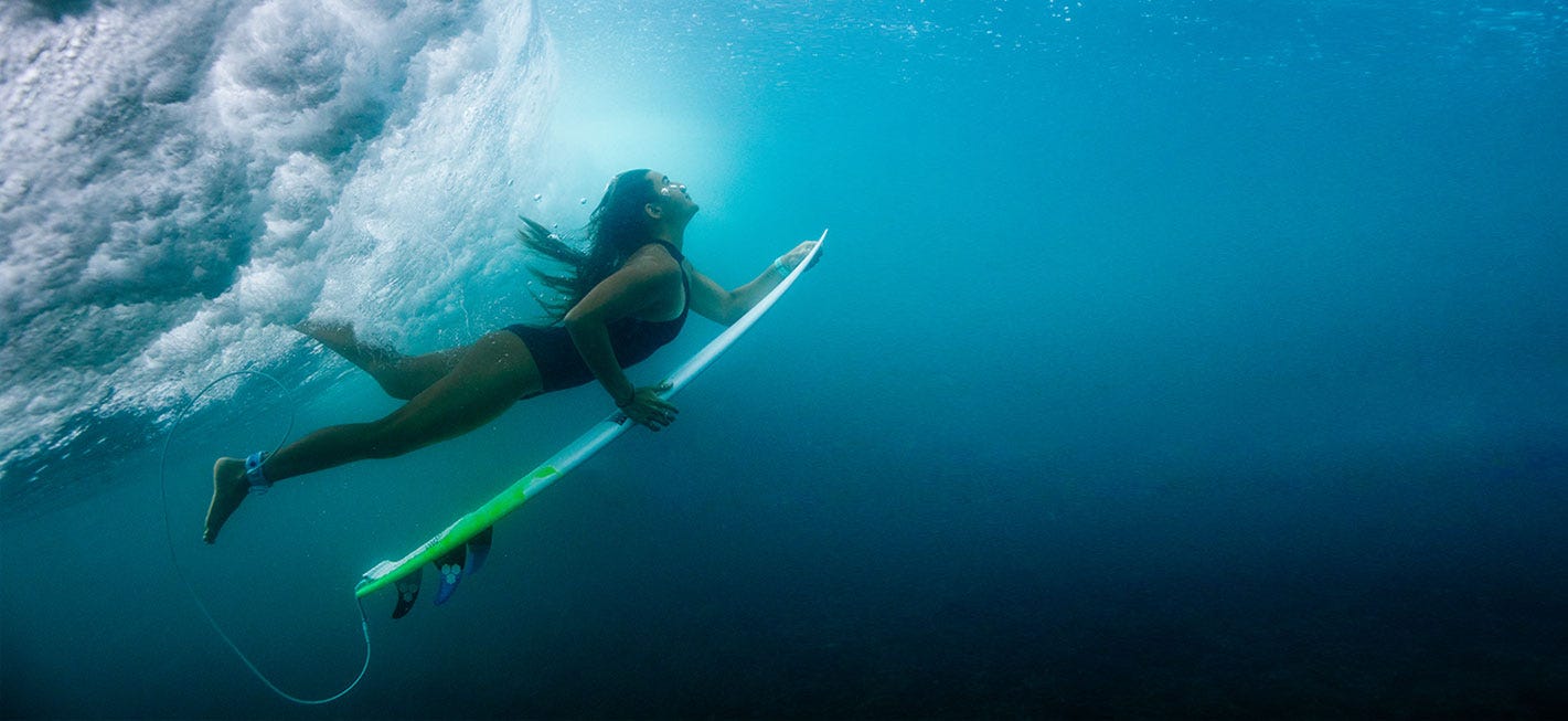 Surfer swimming under a wave with her board