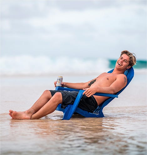 Morgan Cibilic sitting on a deck chair on the beach