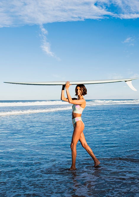 Victoria Vergara carrying a surfboard