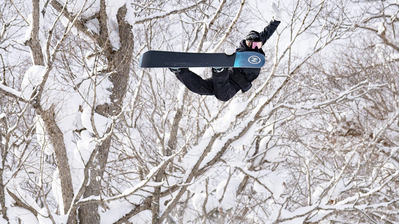 Rip Curl snowboarder jumping through a tree