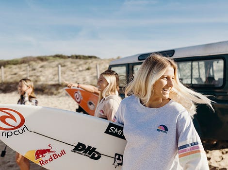 Molly Picklum carrying a surfboard in France